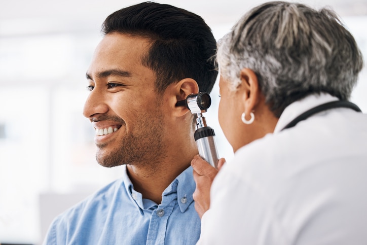doctor check patient ear, healthcare and medical consultation at hospital with otolaryngology specialist. happy man and physician woman with otoscope, test for hearing problem and health insurance