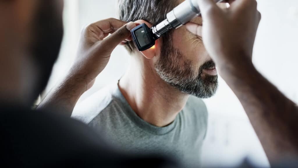 physician examining patient ear with otoscope during hospital consultation
